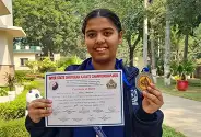 Pearl Bhatia holding her karate championship certificate and medal
